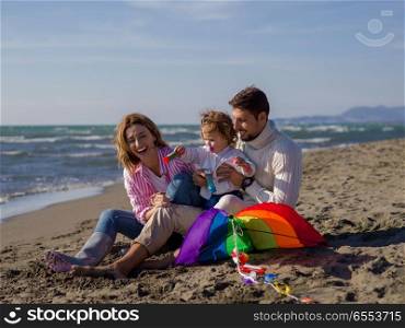Young family enjoying vecation during autumn day. Family with little daughter resting and having fun making soap bubble at beach during autumn day