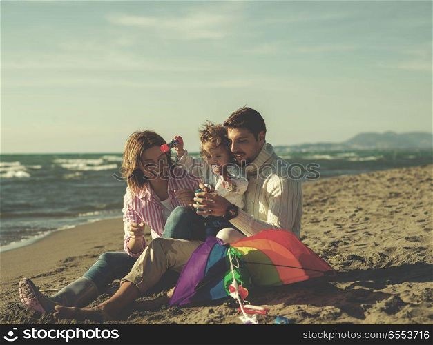 Young family enjoying vecation during autumn day. Family with little daughter resting and having fun making soap bubble at beach during autumn day colored filter