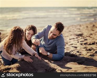 Young family enjoying vecation during autumn day. Family with little daughter resting and having fun at beach during autumn day colored filter