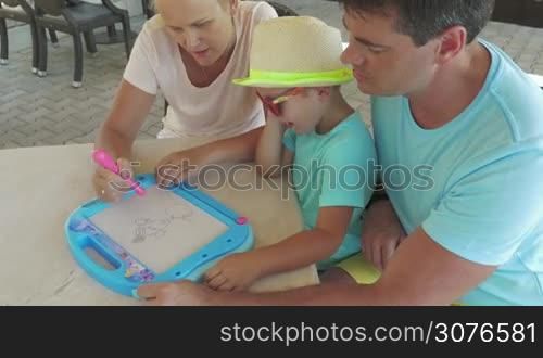 Young family entertainment mother painting some animal on magnet kids drawing board top view