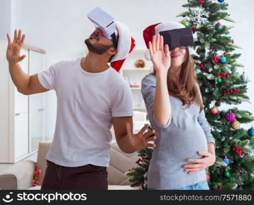 Young family expecting child baby wearing virtual reality VR glasses. Young family expecting child baby wearing virtual reality VR gla