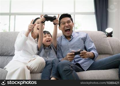 young family, father, mother and son watching TV and playing game feel exciting together in living room, happy family concept