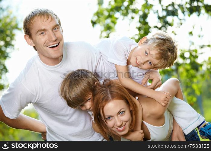 Young family from four members has fun in a summer garden