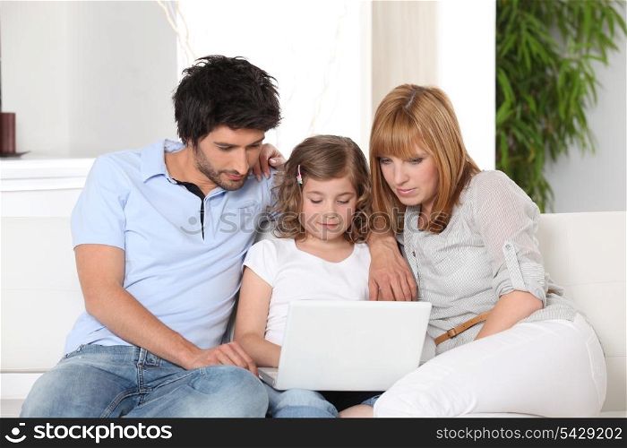 Young family gathered on the sofa with laptop