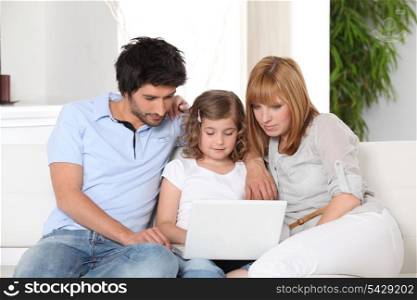 Young family gathered on the sofa with laptop