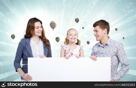 Young family. Happy family of three holding white blank banner. Place for text