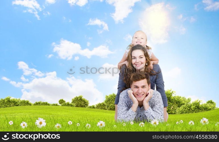 Young family. Happy family of three lying on green grass