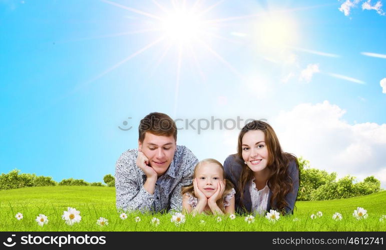 Young family. Happy family of three lying on green grass