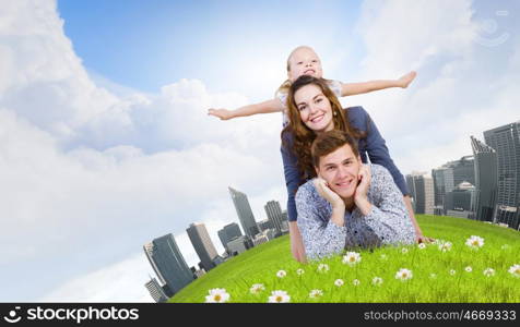 Young family. Happy family of three lying on green grass