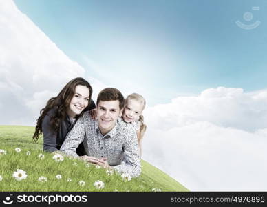 Young family. Happy family of three lying on green grass