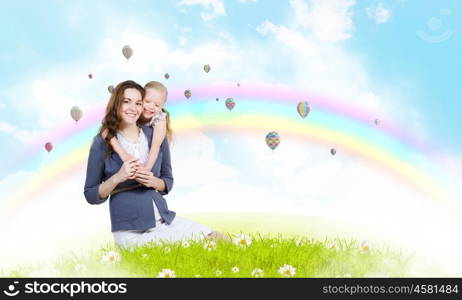 Young family. Happy mother with daughter sitting on green grass