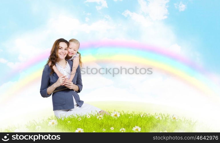 Young family. Happy mother with daughter sitting on green grass