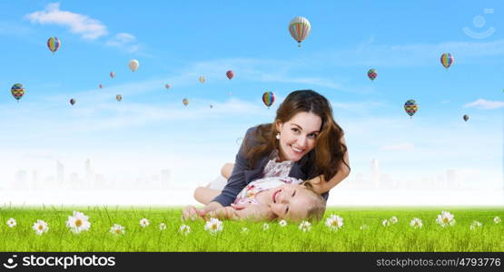 Young family. Happy mother with daughter sitting on green grass