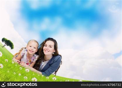 Young family. Happy mother with daughter sitting on green grass