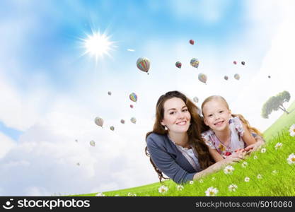 Young family. Happy mother with daughter sitting on green grass