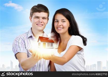 Young family. Happy young couple holding model of house on palms