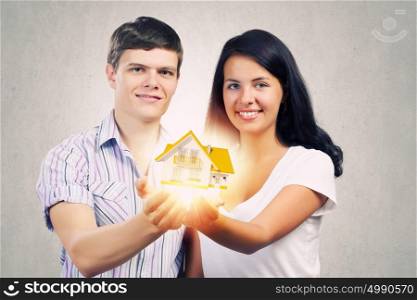 Young family. Happy young couple holding model of house on palms