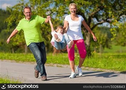 Young family having a walk running on a path and letting the kid fly high