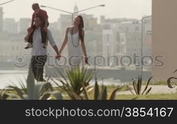 Young family having fun and relaxing in city park with sea view during holidays