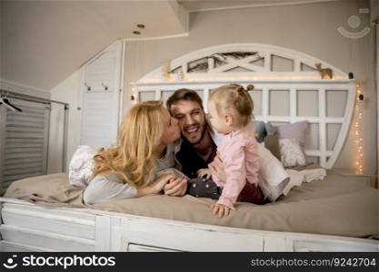 Young family having fun on the bed in the room