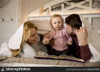 Young family having fun on the bed in the room