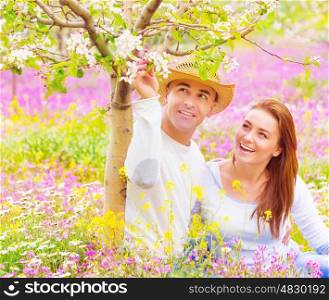 Young family having fun outdoors, cute girl with attractive guy looking on blooming flowers, romantic relationship, love and happiness concept