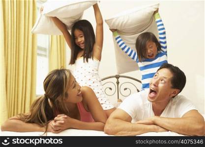 Young Family Having Pillow Fight In Bedroom