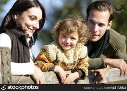 Young family leaning against fence