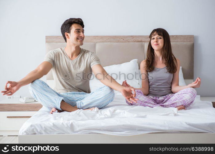 Young family meditating in the bed bedroom