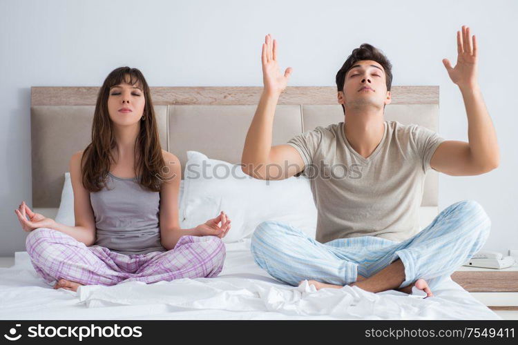 Young family meditating in the bed bedroom. The young family meditating in the bed bedroom