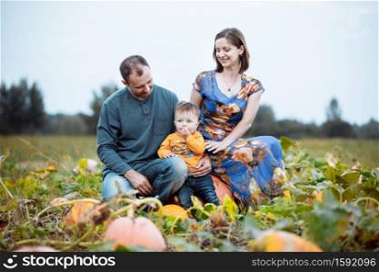 young family, mom, dad and little boy spending time at the pumpkin&rsquo;s farm. Fall time. American holidays - Halloween and Thanksgiving Day. young family, mom, dad and little boy spending time at the pumpkin&rsquo;s farm. Fall time. American holidays - Halloween and Thanksgiving Day.