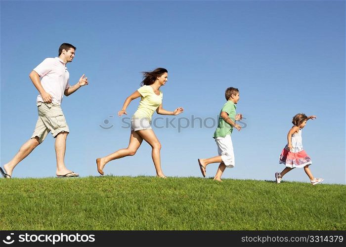 Young family, parents with children, running through field