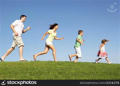 Young family, parents with children, running through field