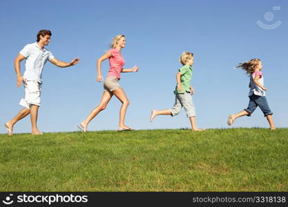 Young family, parents with children, running through field