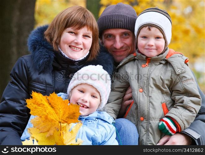 Young family (parents with small children) in golden autumn city park