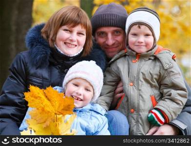 Young family (parents with small children) in golden autumn city park