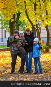 Young family (parents with small children) in golden autumn city park