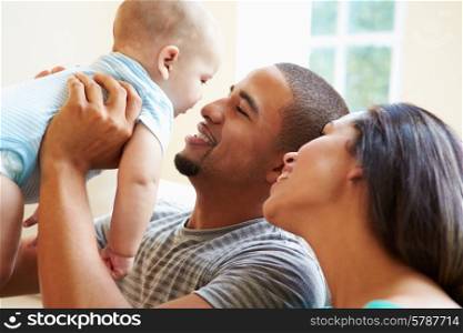 Young Family Playing With Happy Baby Son At Home