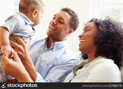 Young Family Playing With Happy Baby Son At Home