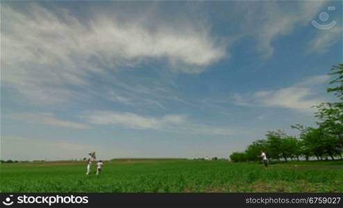 Young Family Playing With Kite In Field