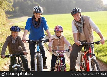 Young family pose with bikes in park