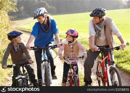 Young family pose with bikes in park