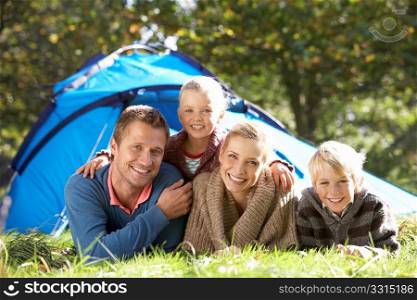 Young family poses outside of tent