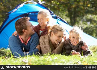 Young family poses outside of tent