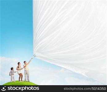 Young family pulling banner. Father and son pulling blank banner. Place for text