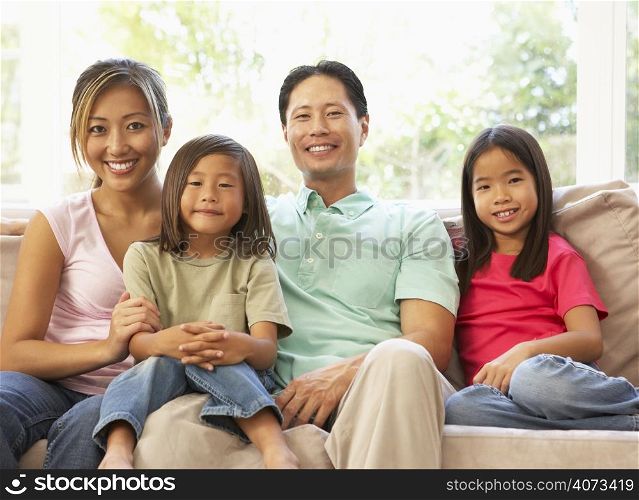 Young Family Relaxing On Sofa At Home
