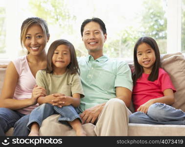 Young Family Relaxing On Sofa At Home