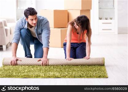 Young family rolling carpet at new apartment