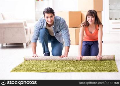Young family rolling carpet at new apartment