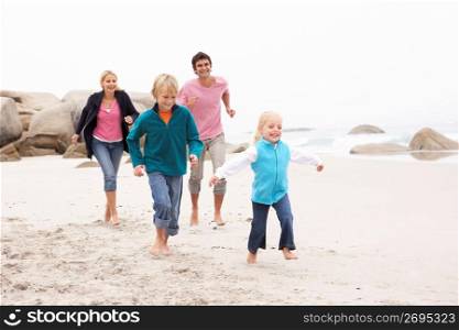 Young Family Running Along Winter Beach